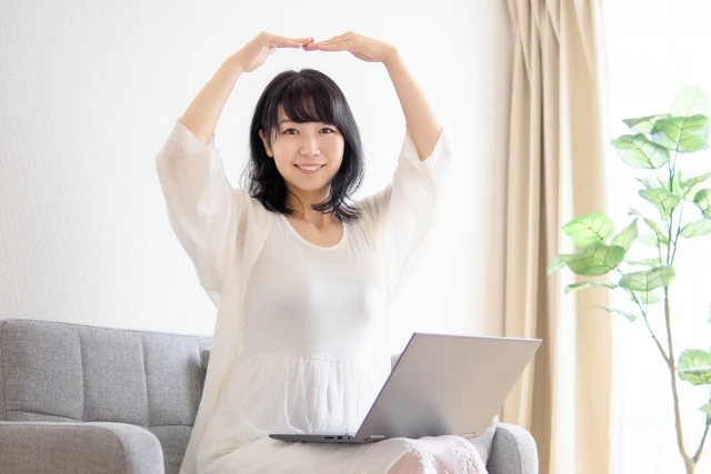 パソコンの前でOKサインをする女性