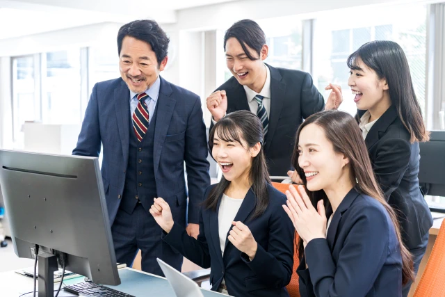 パソコンの前で喜ぶ男女