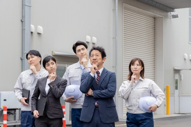 工場の前で考える男女